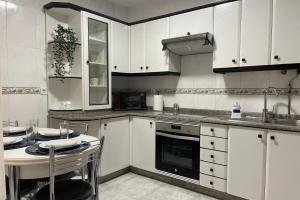 菲尼斯特雷SanMar的厨房配有白色橱柜、桌子和水槽。