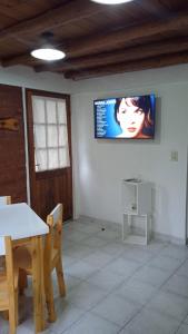 埃斯克尔Cabaña Rayen的一间设有桌子和墙上电视的房间