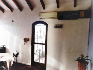 戈多伊克鲁斯Departamento 1º P, 2 personas, WIFI, confortable, mucha luz natural的白色墙壁上的一扇门,上面有桌子和植物