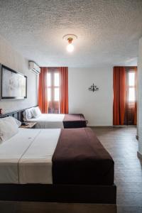 瓜达拉哈拉Hotel Don Quijote Plaza - Guadalajara Centro Historico的配有橙色窗帘的酒店客房的两张床