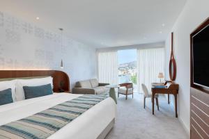 利马索尔Parklane, a Luxury Collection Resort & Spa, Limassol的酒店客房带一张大床和一把椅子