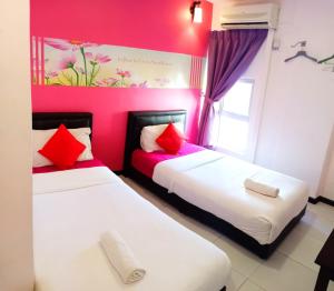 马六甲Sweet Memories Hotel的配有粉红色墙壁的客房内的两张床