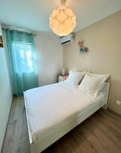 珀蒂堡Appartement Idéal的一间卧室配有一张带白色床单和吊灯的床。