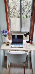 切尔滕纳姆Beach Garden Getaway的一张桌子,上面有一台笔记本电脑,放在窗户前
