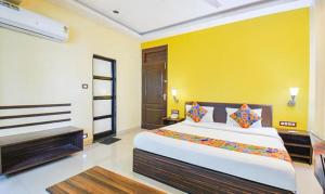 浦那FabHotel Span Executive的一间卧室设有一张大床和黄色的墙壁