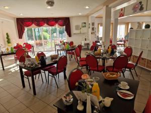 布尔格斯普瓦尔德斯罗斯酒店的用餐室配有桌子和红色椅子