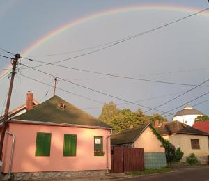 锡尔沃斯瓦里德Liána Vendégház的白色房子上方的彩虹,有绿色百叶窗