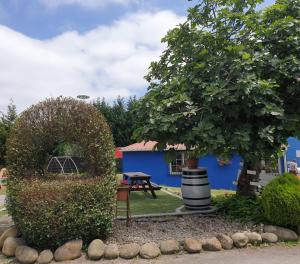 CarrenoPensión Tabaza的一座花园,花园内有蓝色的建筑和一棵树