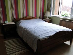 鲁汶Feel at home in Leuven的卧室内的一张床位,卧室拥有条纹墙和窗户