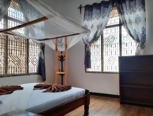 南威Kajificheni House的一间卧室设有天蓬床和窗户。