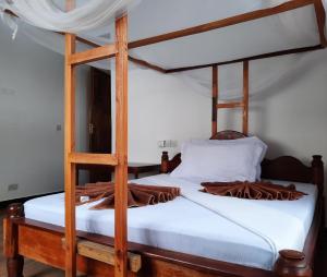 南威Kajificheni House的一间卧室配有一张带白色床单的木制双层床