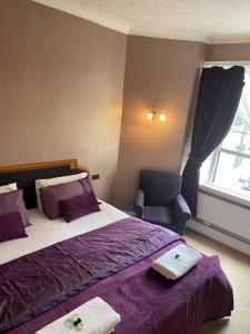 罗切斯特皇家维多利亚与布尔酒店的一间卧室配有一张带紫色床单的床和一把椅子