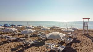 利尼亚诺萨比亚多罗雅典娜酒店 的海滩上的一组椅子和遮阳伞