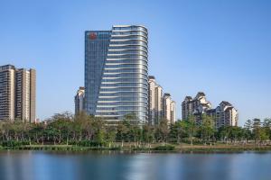 广州广州南沙越秀喜来登酒店的一座高大的建筑,靠近一个城市前面的湖泊