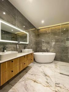 拉各斯Studio 6的浴室配有2个盥洗盆、浴缸和镜子