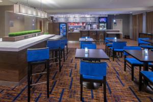 奥尔巴尼Courtyard by Marriott Albany的一间设有蓝色桌椅的餐厅和一间酒吧