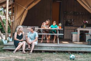 霍尔滕Glamping Holten luxe safaritent 1的一群人坐在野餐桌旁