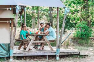 霍尔滕Glamping Holten luxe safaritent 2的坐在凉亭野餐桌旁的家庭