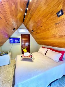 乌巴雅拉Pousada Vale da Neblina的一间卧室设有一张带木制天花板的大床