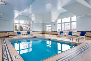 巴里巴里福朋喜来登酒店的一座蓝色的游泳池,在建筑里摆放着椅子