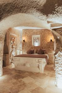 乌奇希萨尔Harem Suites Cappadocia的卧室配有一张石墙内的大床