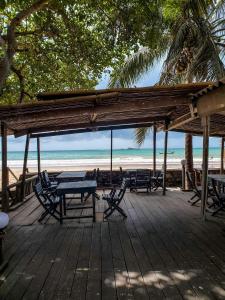 BusuaBusua Inn的海滩上带桌椅的木制甲板