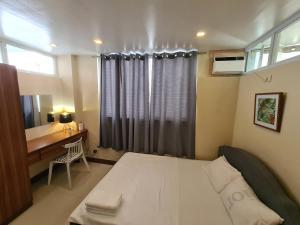 大雅台Serenity Home near Ayala Malls Serin的一间卧室配有一张床、一张书桌和一个窗户。