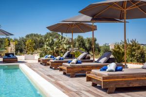 奥斯图尼Villa Gufo的游泳池旁一排带遮阳伞的躺椅