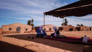 姆哈米德Camp Sahara Dunes的两人坐在沙漠的伞下