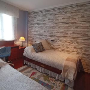 莫阿尼亚MAR AVILLA ESPECTACULAR RIA DE VIGO con PARKING PLAYA的一间卧室设有两张床和砖墙