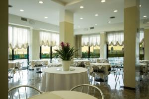 里米尼诺德伊斯特酒店的一间设有白色桌椅的餐厅,