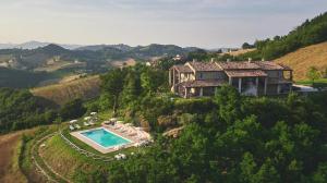乌尔比诺Country House Ca'Balsomino的享有山丘上房屋的空中景致,设有游泳池