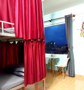 大叻Hugo's Family的一间卧室配有一张带红色窗帘和桌子的双层床