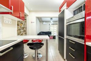 雅典Άνετο & ήσυχο διαμέρισμα για 4的厨房配有红色橱柜和带凳子的台面