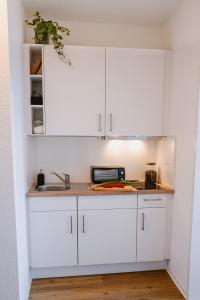 维斯马Designoase für 3 mit Blick auf den Wismarer Hafen的厨房配有白色橱柜和水槽