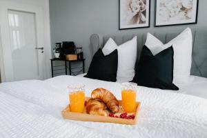 维斯马Designoase für 3 mit Blick auf den Wismarer Hafen的床上的羊角面包和橙汁托盘