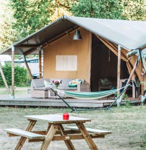 霍尔滕Glamping Holten luxe safaritent 2的帐篷配有野餐桌和吊床