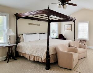 卡莱尔Pheasant Field Bed and Breakfast的一间卧室配有一张天蓬床和一把椅子