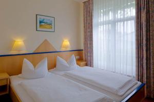 马尔肖Sporthotel Malchow Hotel Garni HP ist möglich的一间卧室配有一张带白色床单的床和一扇窗户。