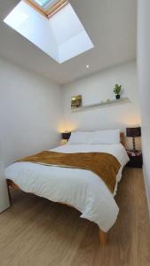 Cherry HintonModern Spacious Detached Cottage in Cambridge的一间卧室配有一张带白色床单和天窗的床。