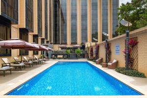 达累斯萨拉姆Element by Westin Hotel Dar es Salaam的一座带椅子和遮阳伞的游泳池位于一座建筑旁边