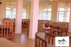 ThikaRocky river falls resort的餐厅设有木桌、椅子和窗户。