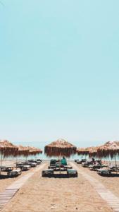 依拉佩特拉SeaSideRooms的海滩上设有椅子和草伞,还有大海