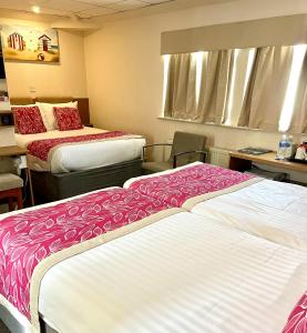 布莱克浦伯翰姆伍德法院酒店的酒店客房带两张红色和白色的床单