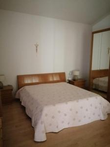 特拉尼B&B dei Girasoli的卧室配有一张白色大床,墙上有十字架