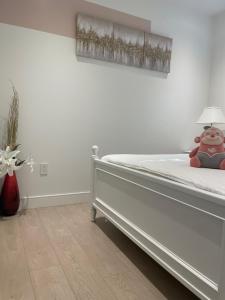 温哥华Brand new 1Queenbed family suite near UBC的一间白色的卧室,床上有一只动物填充