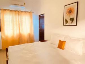 科钦Fortis Rooms的卧室配有一张白色床,墙上挂着向日葵照片