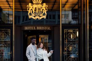 维也纳Hotel Bristol, a Luxury Collection Hotel, Vienna的站在建筑物前面的男人和女人