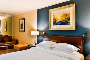 希灵登喜来登伦敦希思罗天际线酒店的卧室配有一张床,墙上挂有绘画作品