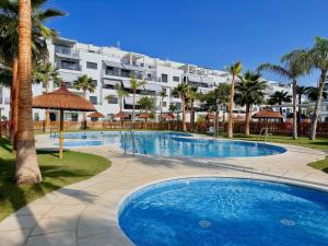 莫特里尔Apartamento Aguacate Beach Golf的一座棕榈树游泳池和一座大型建筑